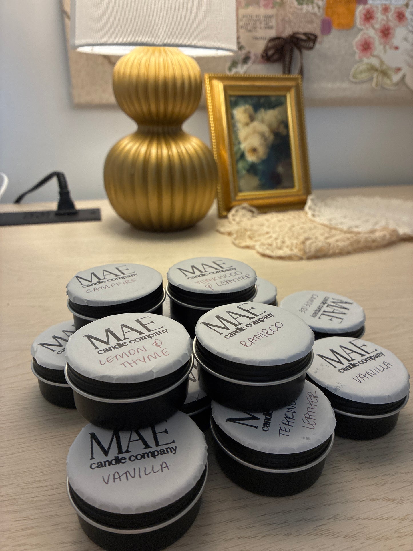 Black tin candles labeled with scents all stacked up. 