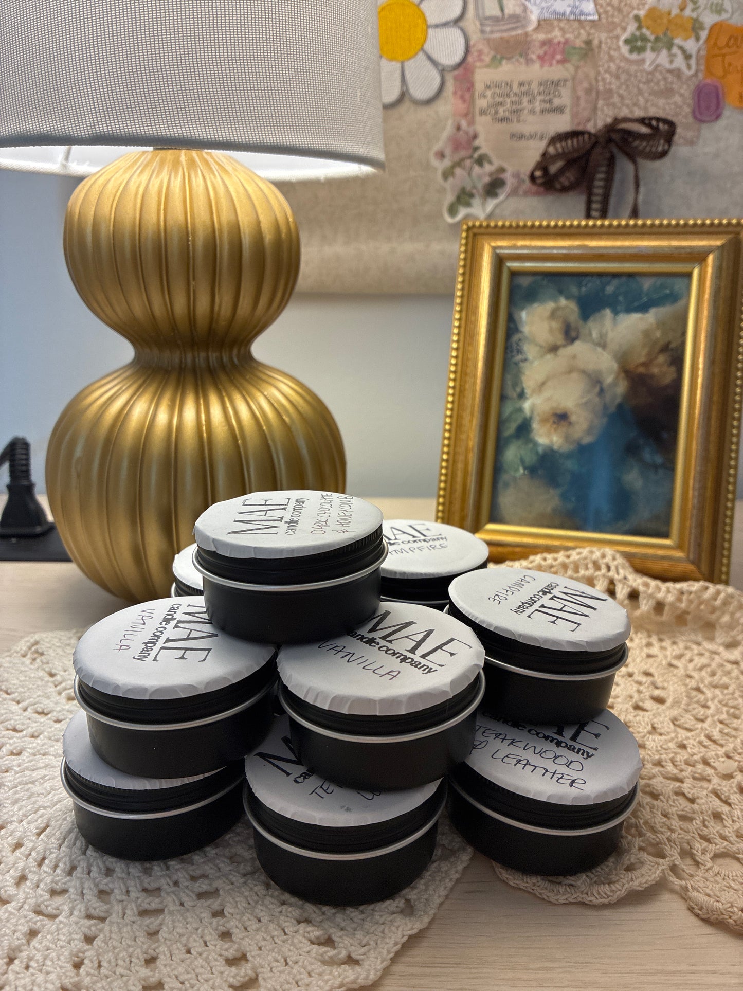 Black tin candles labeled with scents all stacked up 